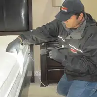 Bed bug inspection technician checking a mattress and bed frame for signs of infestation in Savannah, GA