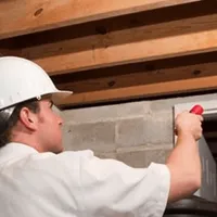 Termite inspection technician checking a basement wall and framing for termite activity in Savannah, GA