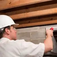 Termite inspection technician checking a basement wall and framing for termite activity in Savannah, GA